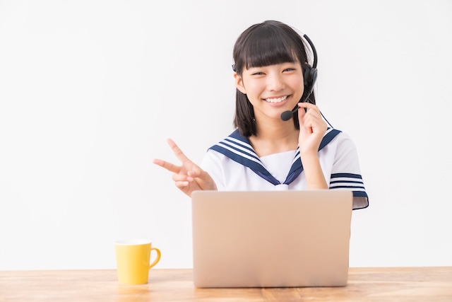 オンライン英会話のレッスンを受けてピースサインをする女子中学生