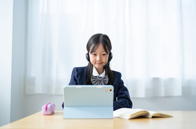 自宅でオンライン英会話レッスンを受ける制服を着た女子中学生