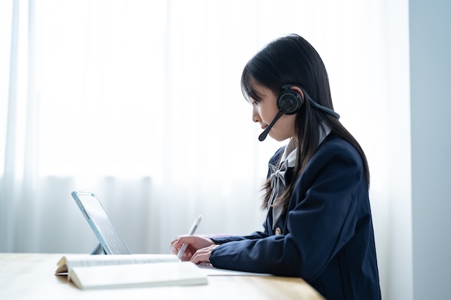 自宅でオンライン英会話レッスンを受ける紺色の制服を着た女子中学生