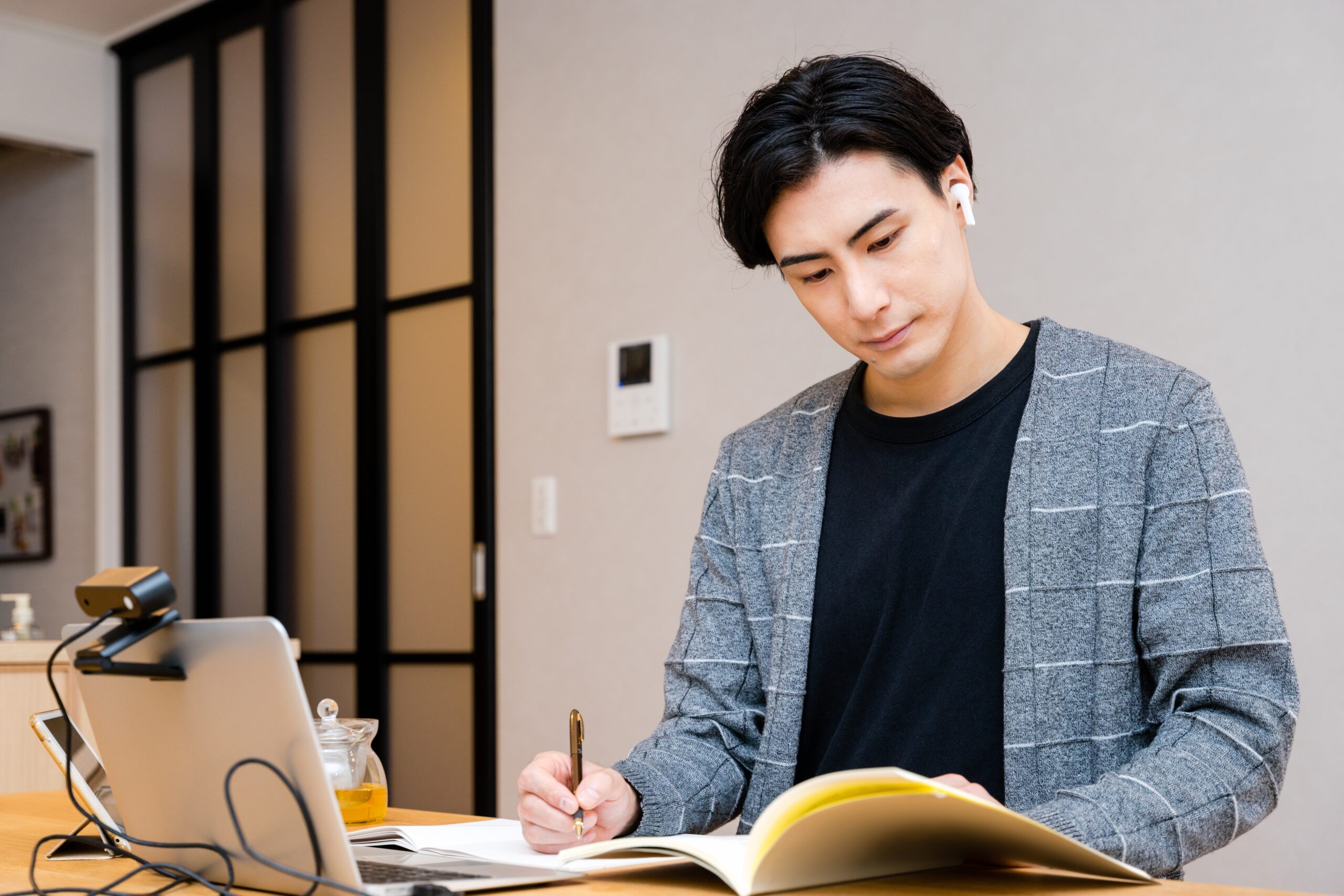 オンライン英会話のレッスンを受けながら自宅で勉強する男性
