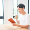自宅で飲み物を片手に勉強する男性
