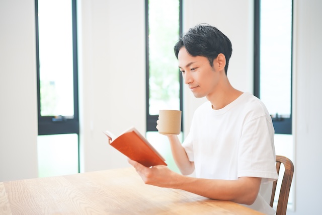 自宅で飲み物を片手に勉強する男性