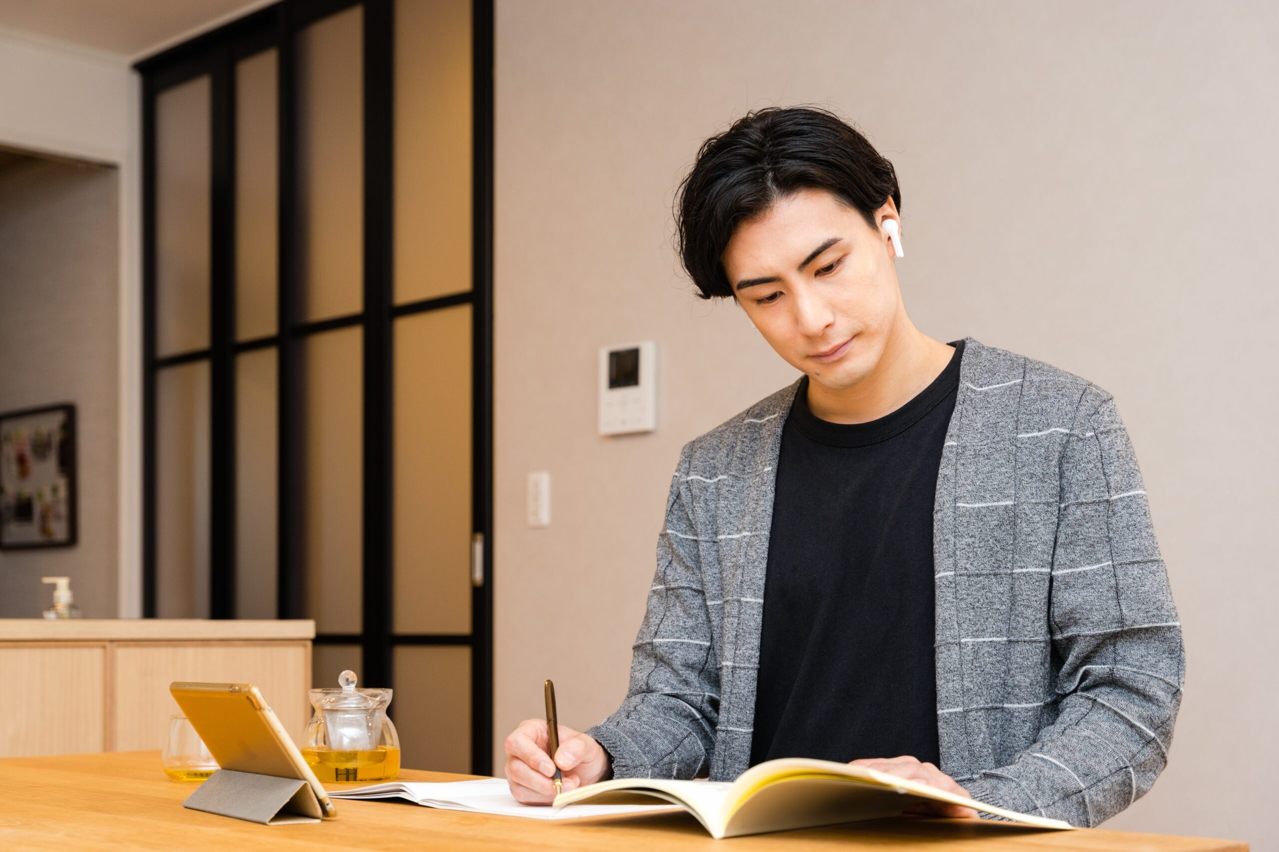 タブレットを見ながらノートを取る男性