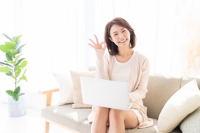 パソコンを膝に乗せながらオッケーを出す女性