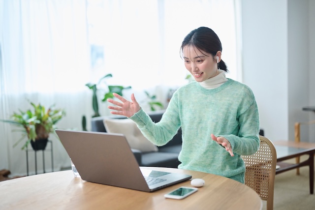 オンライン英会話でジャスチャーを使いながら話す緑色の服を着た女性