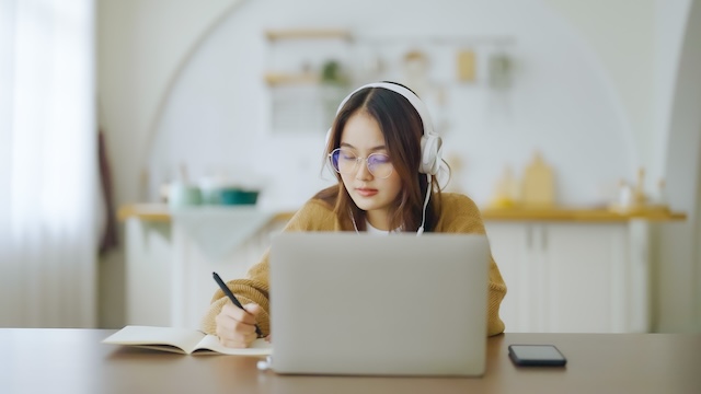 ノートパソコンの前で勉強するメガネをかけた女性