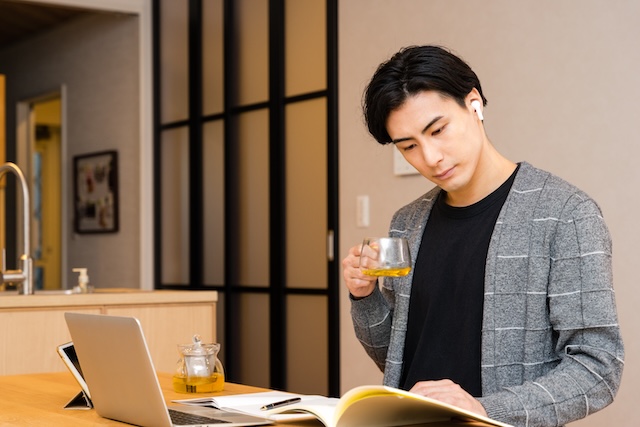 自宅でお茶を片手に勉強する若い男性