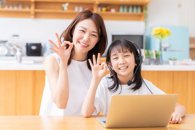 オンライン英会話のレッスンを受けてオッケーサインをする親子