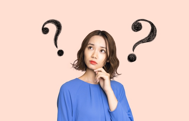 はてなマークが浮かぶ青い服を着た日本人女性
