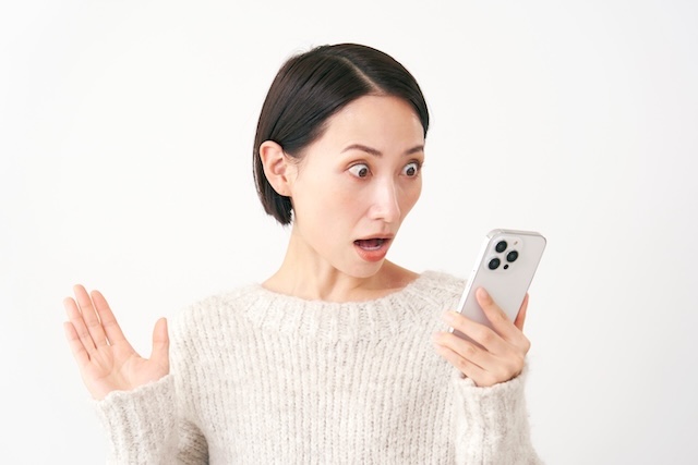 スマートフォンを見て驚く女性